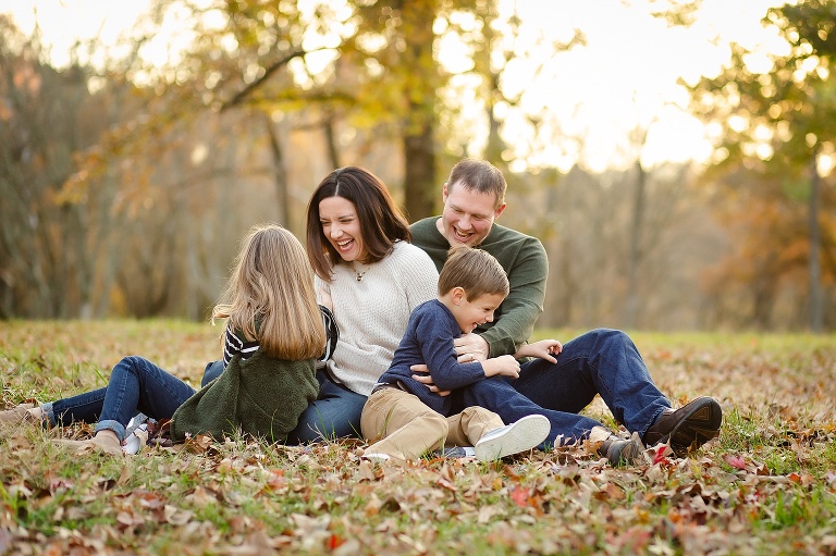 Family sitting on ground in park tickling each other | KGriggs Photography