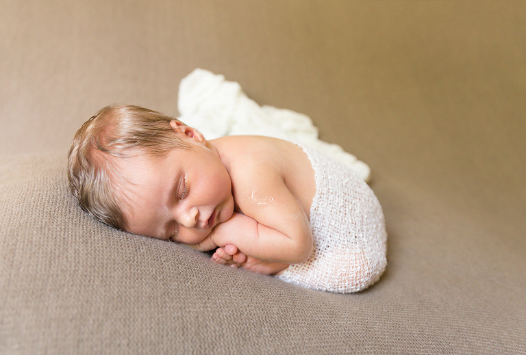Newborn baby with white wrap on a brown blanket | St. Louis Photography