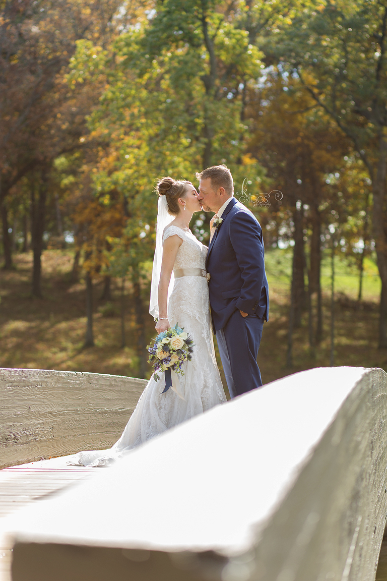 bride and groom standing on bridge kissing | St. Louis Photographers