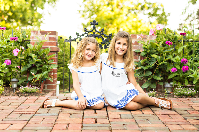 Two girls sitting on the ground smiling at camera. | St. Louis Family Photography