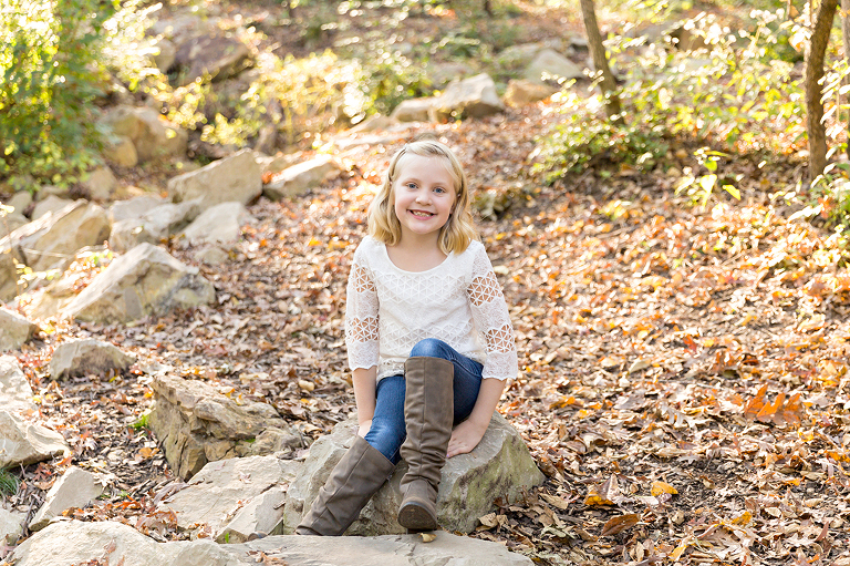 Girl sitting on rock smiling at camera - Longview Farm Park | St. Louis Family Photographer