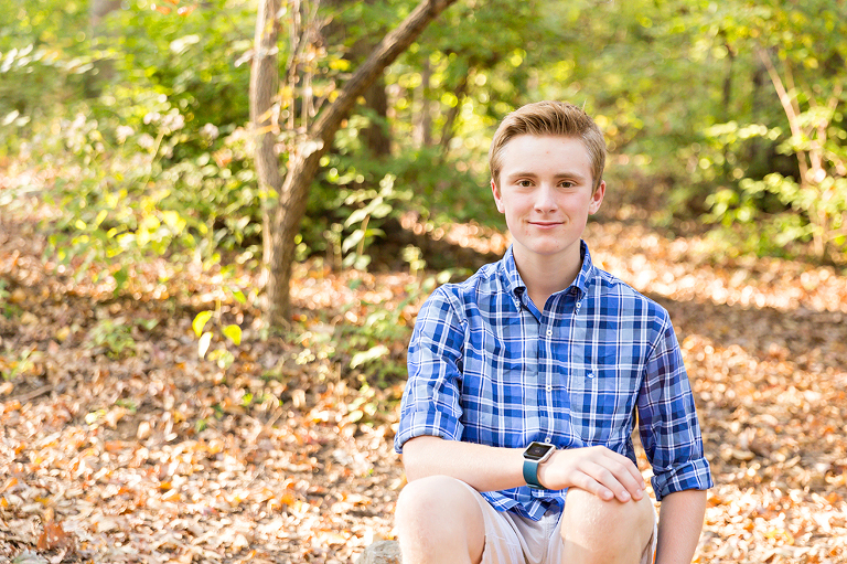 Teenage boy sitting on ground smiling - Longview Farm Park | St. Louis Family Photos