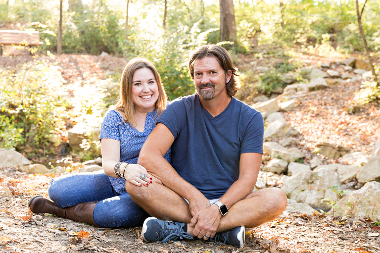 Husband and wife sitting on ground in park - Longview Farm Park | St. Louis Family Photographer