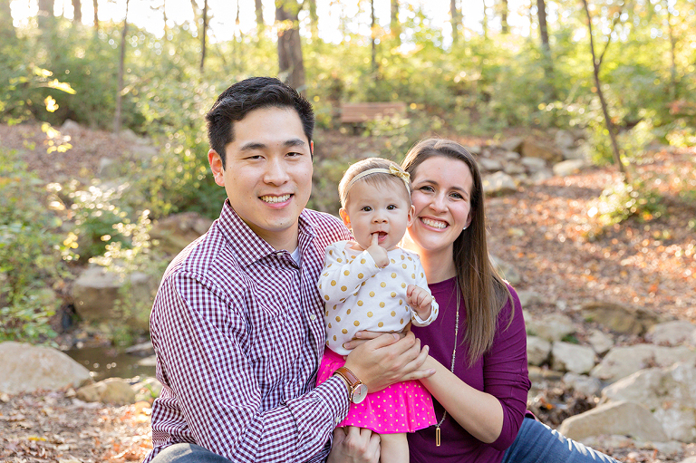 Little girl and her parents sitting on ground - Longview Farm Park | St. Louis Family Photographer