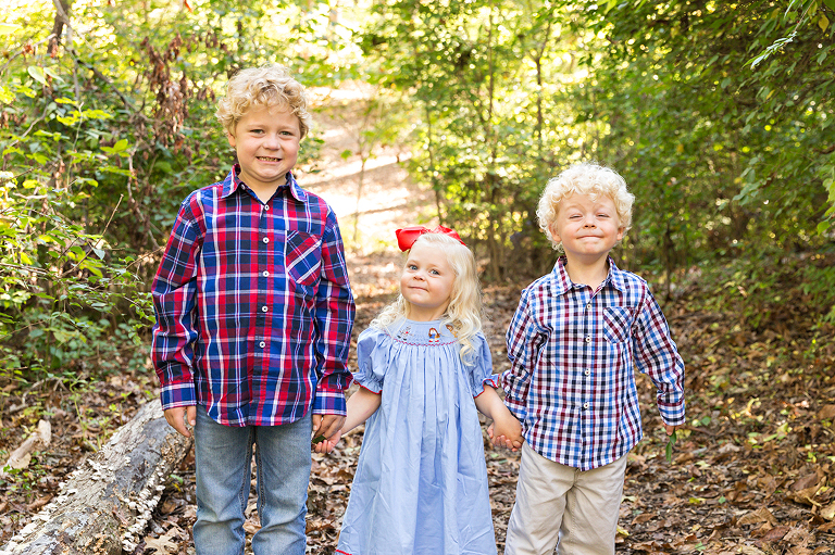 Three children holding hands in wooded area - Longview Farm Park | St. Louis Family Photographer