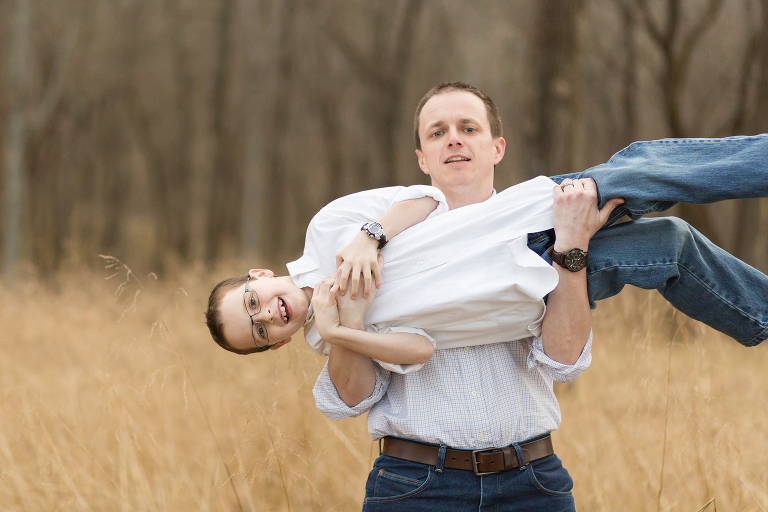 Father picking up young son in playful way | St. Louis Family Photography