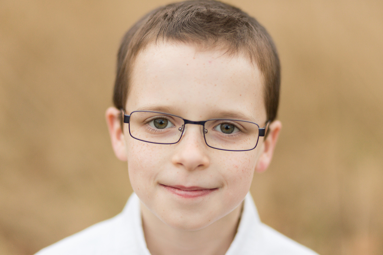 Young boy wearing glasses looking at camera | Kirkwood Family Photographer