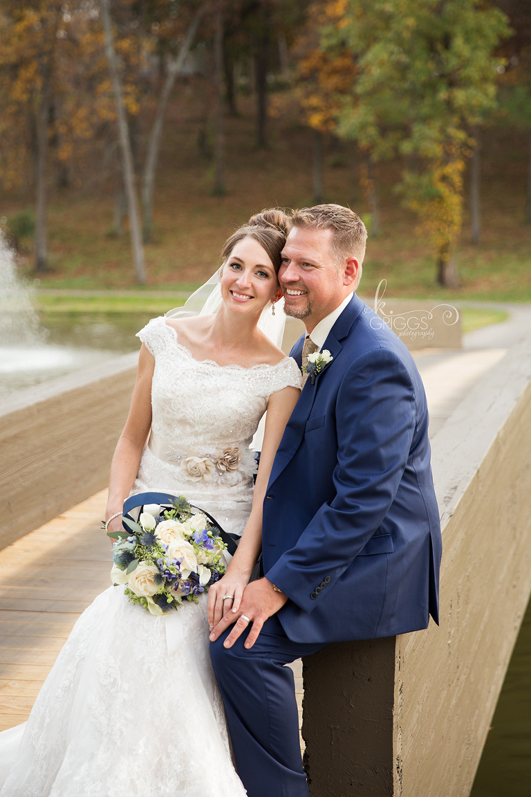 Bride sitting on groom's lap on edge of bridge | St. Louis Photos