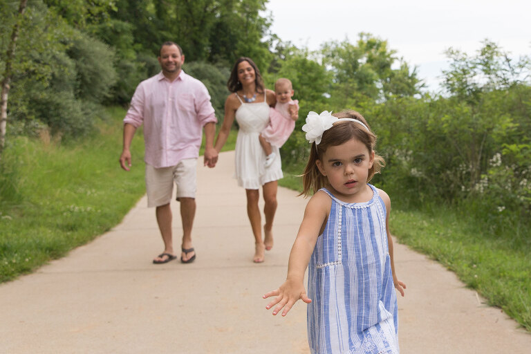 Young girl running toward camera with family behind | KGriggs Photography | St. Louis Family Photographer