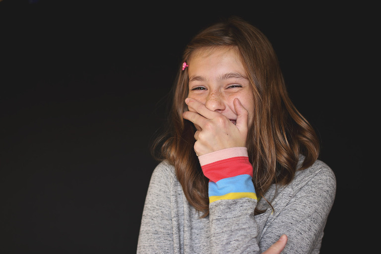 Tween girl covering her mouth while laughing | St. Louis School Photos