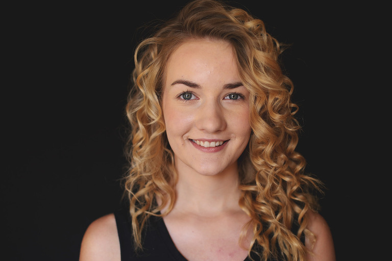 Teenage girl with curly hair smiling at camera | St. Louis School Photographer