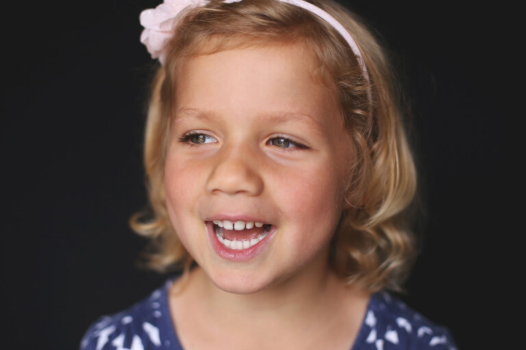 Young girl wearing headband smiling and looking to the side | St. Louis School Photography