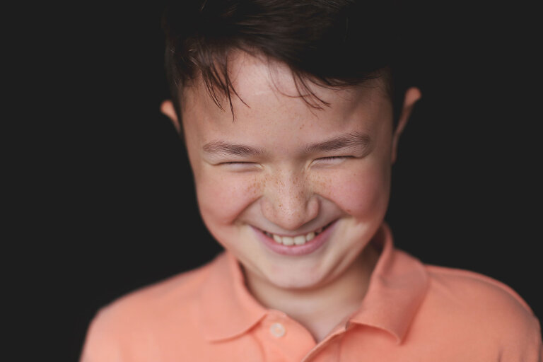 Pre teen boy laughing and looking down | St. Louis School Photographer