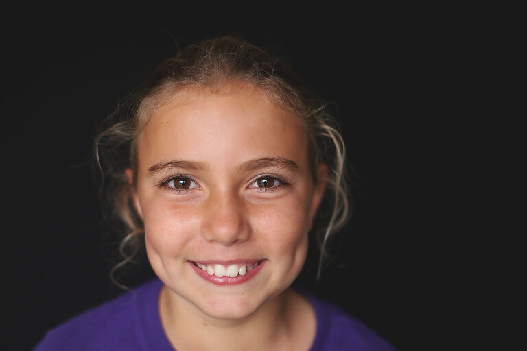 Young girl with big dimples smiling at camera | St. Louis School Photography
