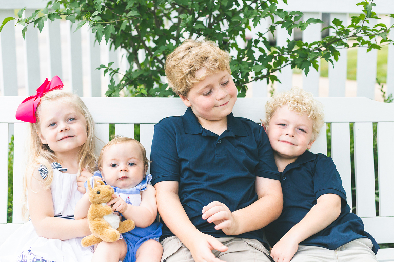 Four siblings sitting together on a white bench | St. Louis Photography