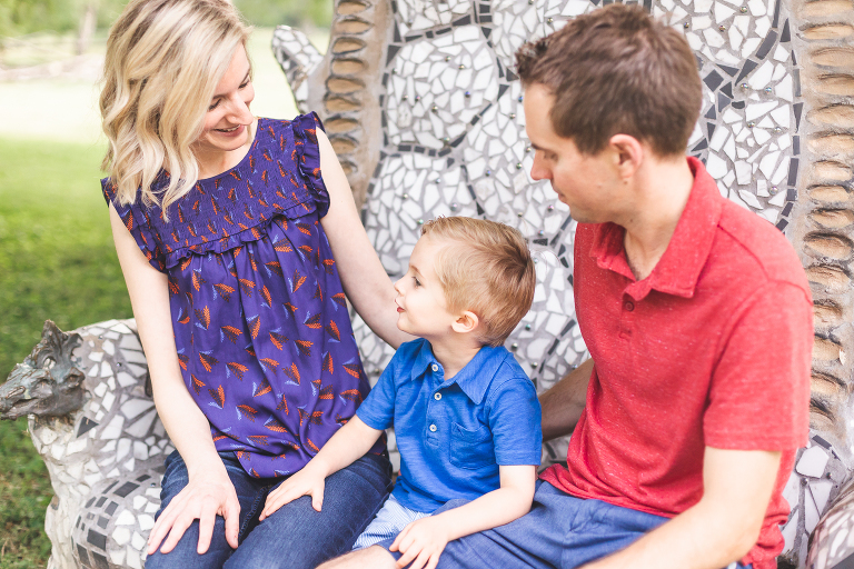 Mom, Dad, and little boy sitting on mosaic chairs in Francis Park | St. Louis Family Photos