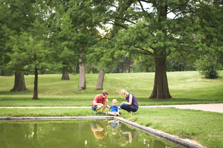 Family of 3 sitting by pond with reflection in Francis Park | Family Photos St. Louis