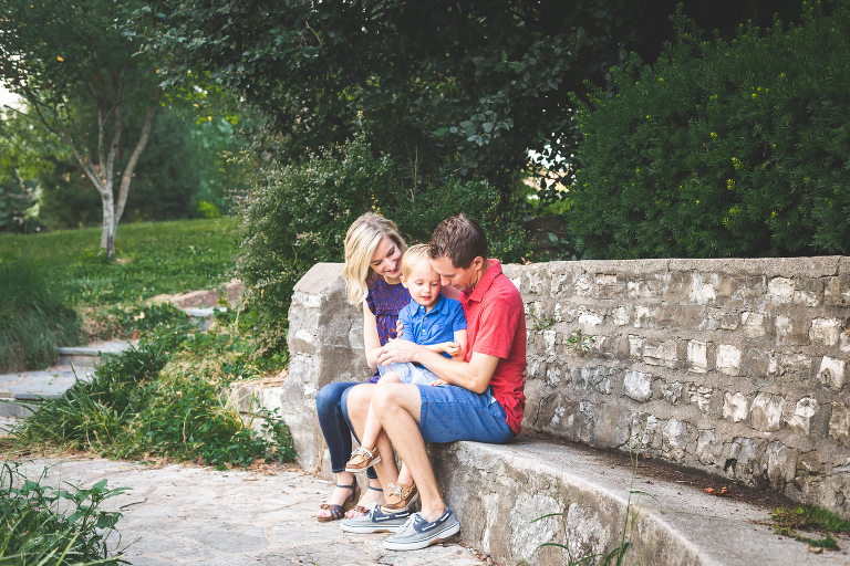 Mom, Dad, and little boy sitting on a rock bench spending time talking | Family Photographers St. Louis