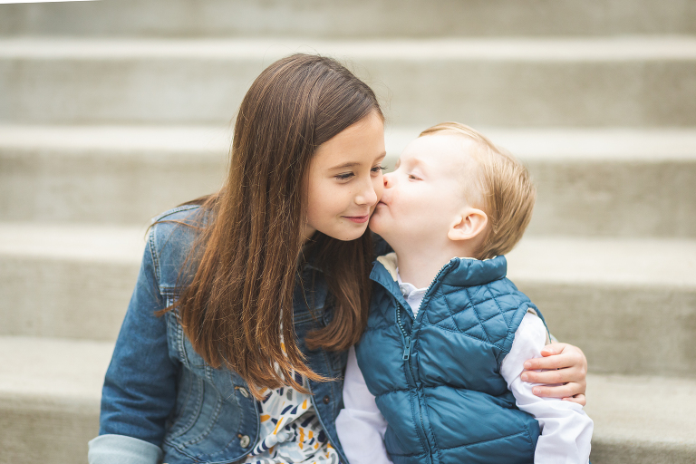 Big sister getting kiss on cheek from little brother at Oak Knoll Park | St. Louis Family Photography