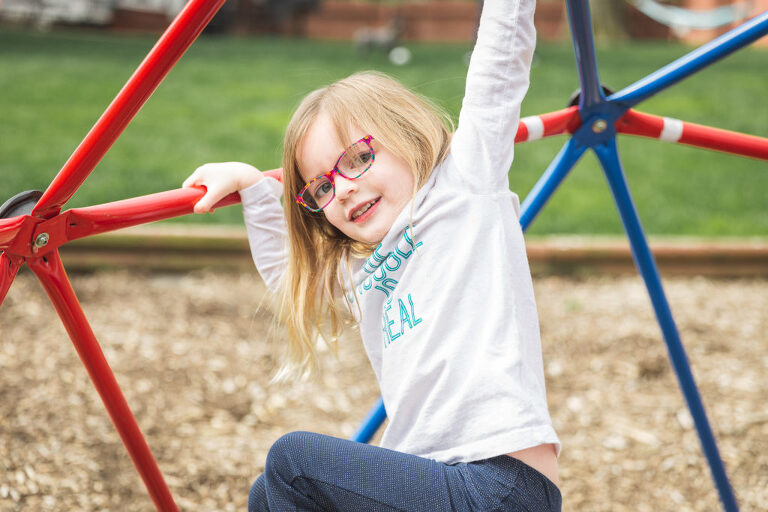 Young girl playing on jungle gym in yard | St. Louis Family Photographer