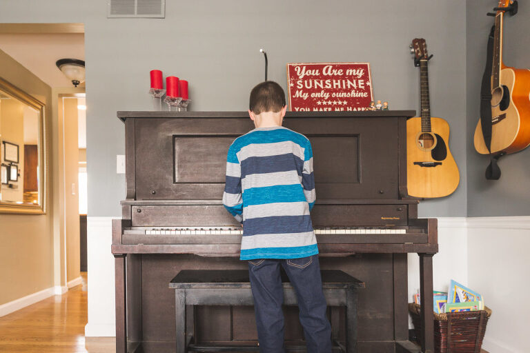 Boy standing in front of piano playing | St. Louis Family Photography