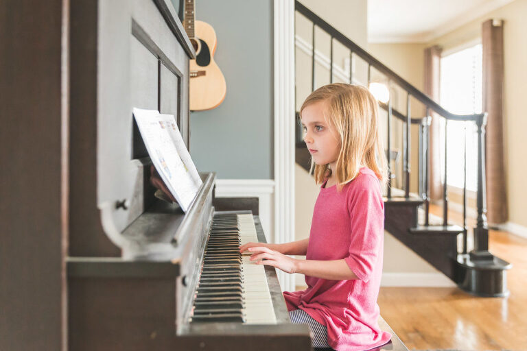 Young girl sitting at piano playing | St. Louis Family Photos