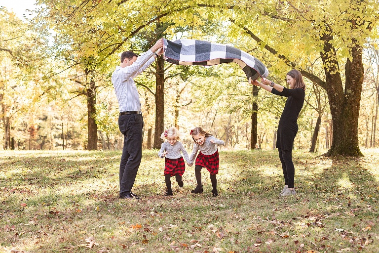 Two girls running under blanket lifted up by parents | STL family photographer