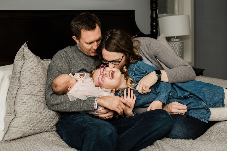 Mom kissing older daughter during in home newborn session | St. Louis Newborn Photographer