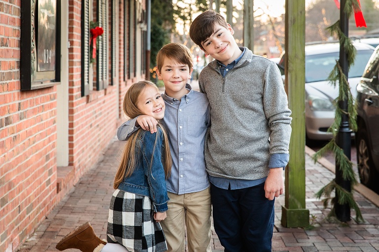 Three siblings standing on sidewalk smiling at camera | KGriggs Photography