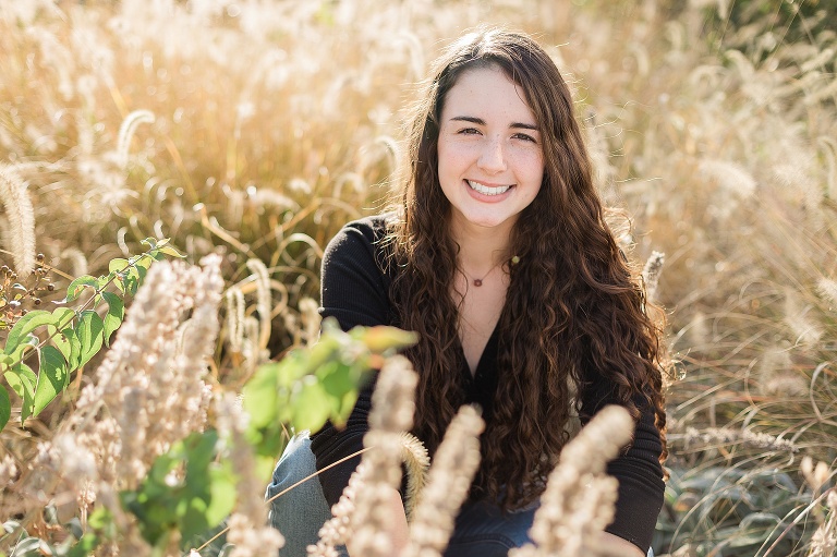 High school senior girl sitting in field of grass at sunset | KGriggs Photography